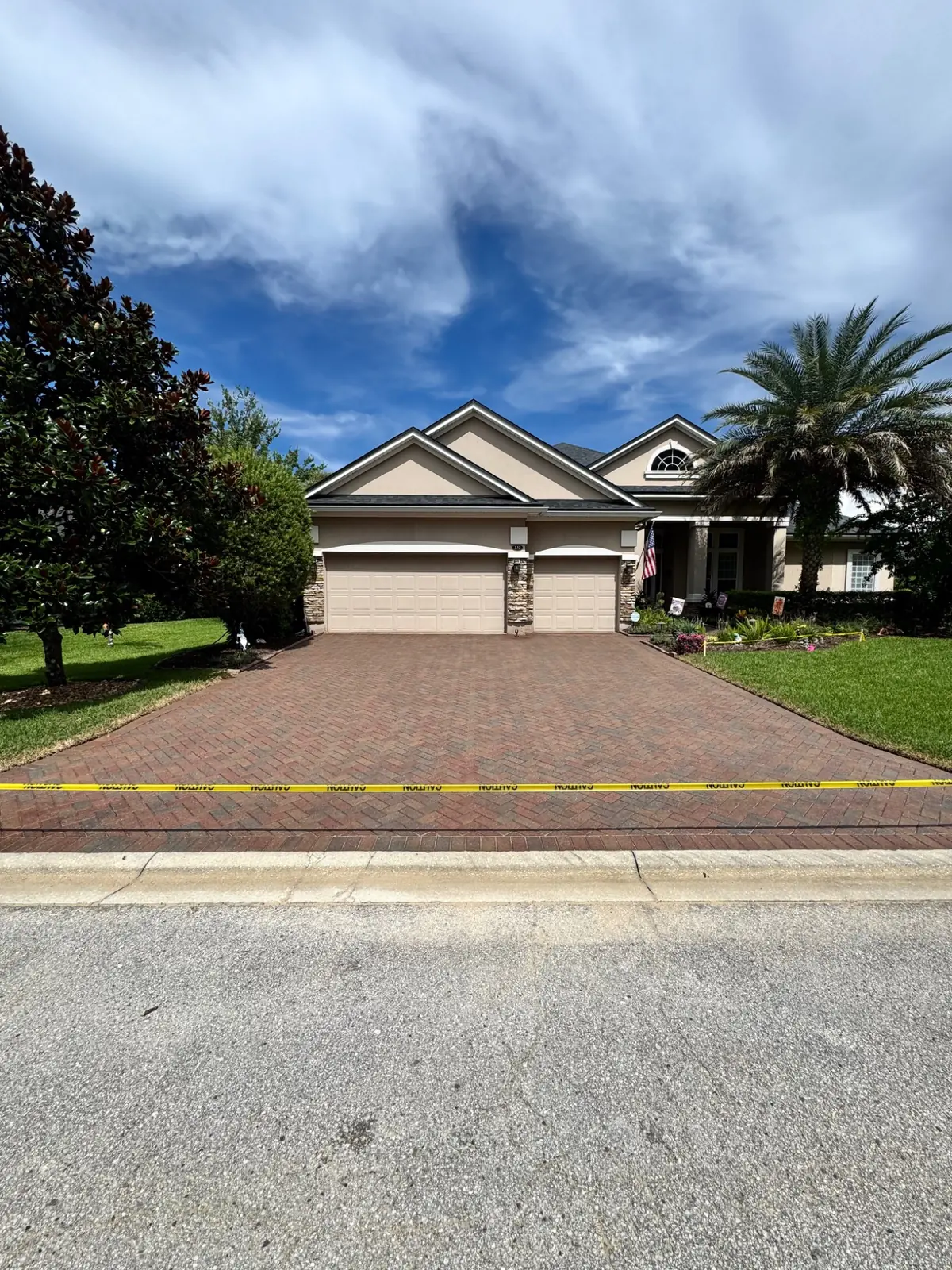 Freshly sealed paver driveway curing behind caution tape