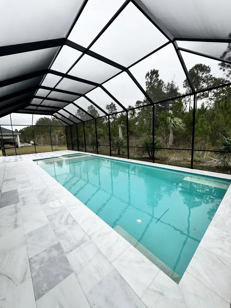 Clean pool deck surrounding a screened-in swimming pool